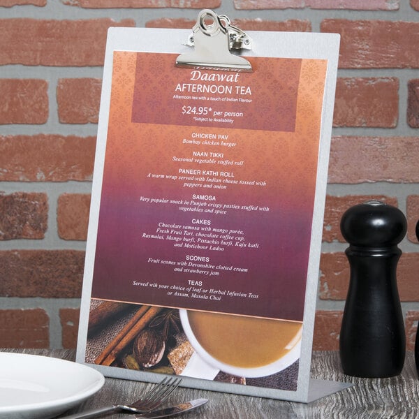 A Menu Solutions aluminum menu tent on a table with a white bowl and a cup of tea.