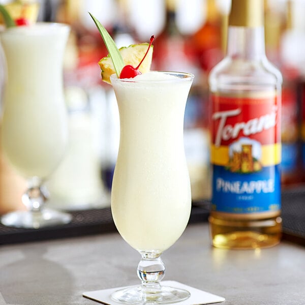 A glass of white liquid flavored with Torani Pineapple Syrup with a cherry on top.