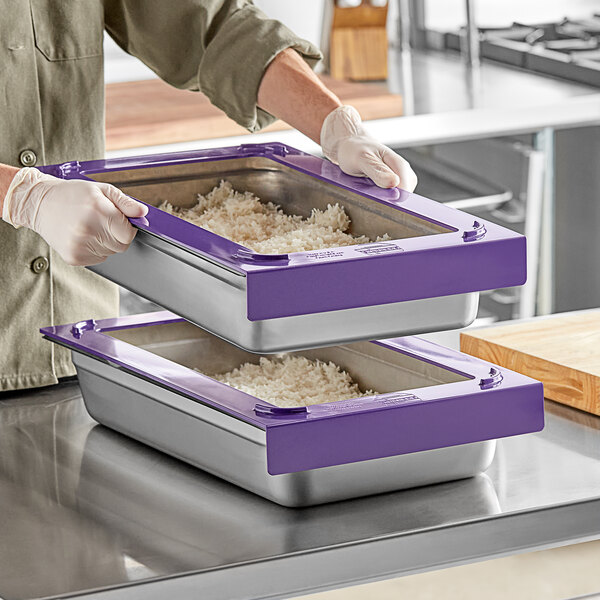 A woman using purple Pan Stackers to hold two full size stainless steel hotel pans of rice.