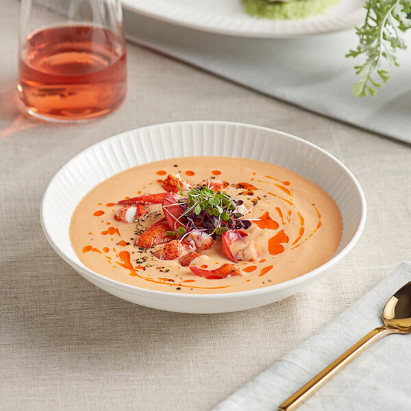 A bowl of soup with strawberries and sprouts in an Acopa Cordelia coupe bowl with a spoon on a napkin.