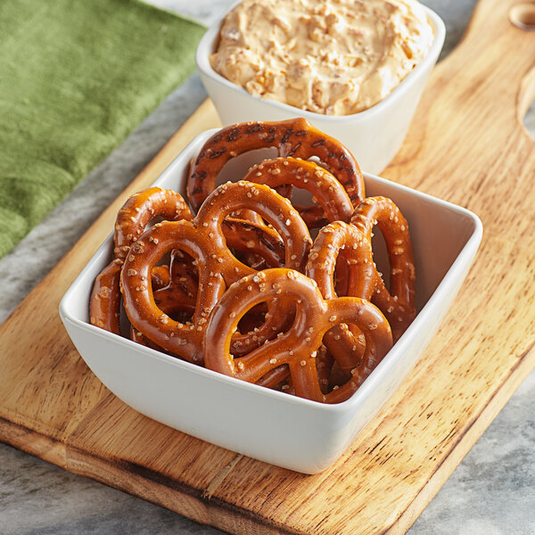A bowl of Snyder's of Hanover pretzels next to a bowl of dip.