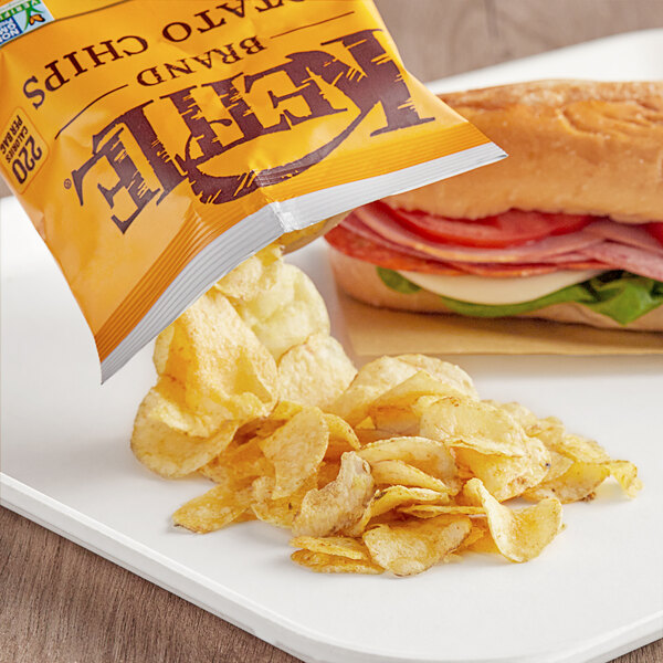 A bag of Kettle Brand Honey Dijon potato chips next to a sandwich.