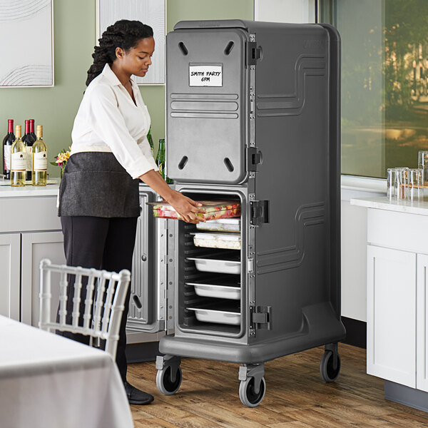 A woman in a professional kitchen using a Cambro Pro Cart Ultra Pan Carrier with two active cold compartments.