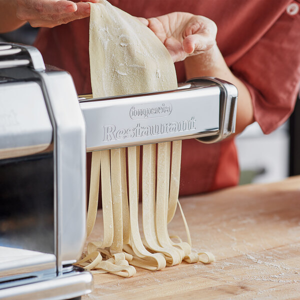 A woman using an Imperia Lasagnette Pasta Cutter to cut pasta on a machine.