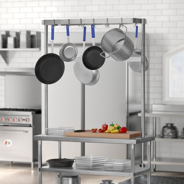 A stainless steel kitchen with pots and pans hanging from a Regency table-mounted pot rack.