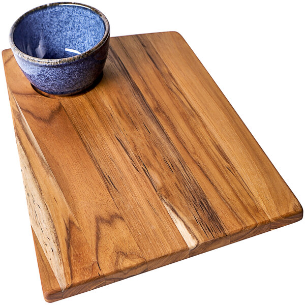 A Teakwood cutting board with a blue bowl in the center.