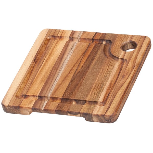 A Teakhaus Edge Grain teakwood cutting board with a hanging hole.