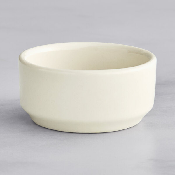 A Oneida Classic porcelain butter cup on a gray surface.