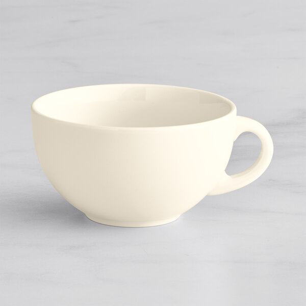 A white Oneida Verge porcelain cappuccino cup with a handle on a marble surface.