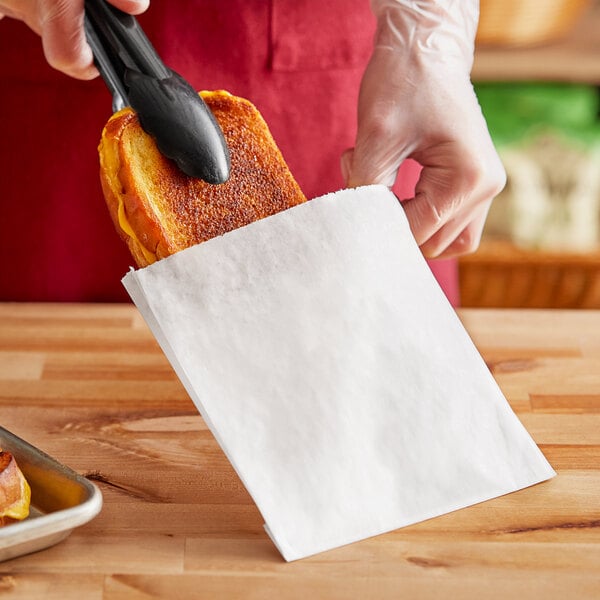 A person putting a sandwich in a Choice white paper sandwich bag.