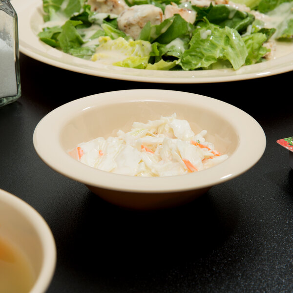 A tan Thunder Group narrow rim melamine monkey dish filled with coleslaw and salad on a table.