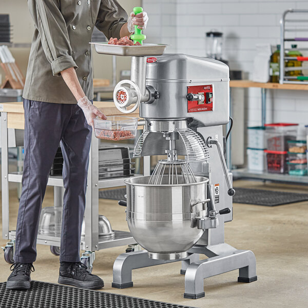 A man using an Avantco planetary floor mixer with meat grinder attachment.