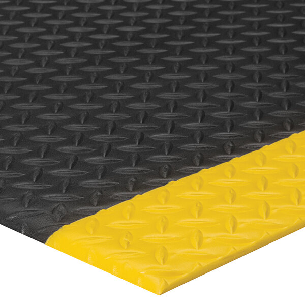 A close up of a black Lavex Diamond Deluxe anti-fatigue mat with yellow diamond borders.
