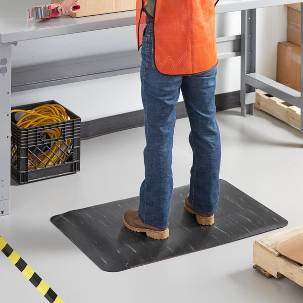 A person standing on a black and white Lavex K-Marble Foot anti-fatigue mat.