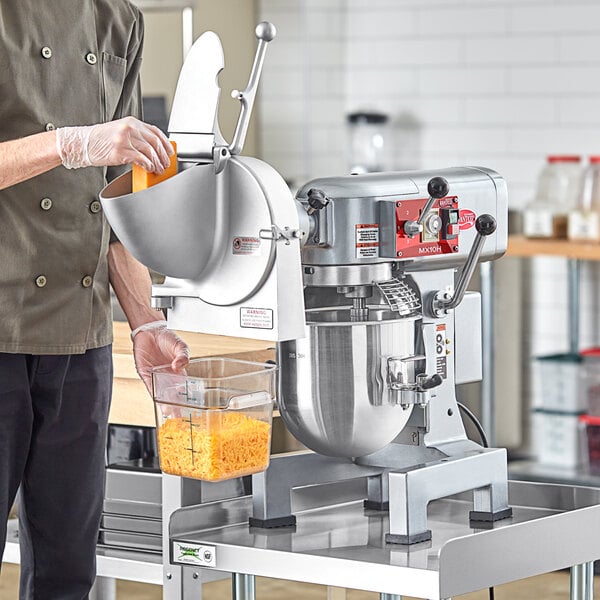 A man in a chef's uniform using an Avantco planetary stand mixer in a professional kitchen.