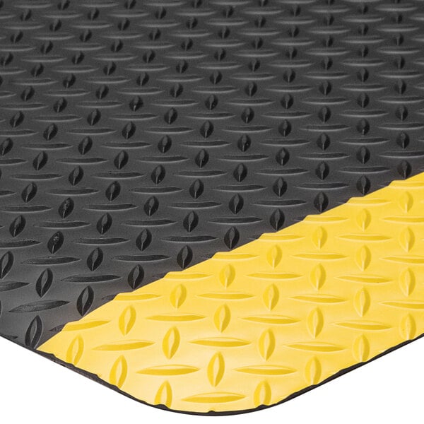 A close up of a black Lavex Diamond Star anti-fatigue mat with yellow diamond borders.
