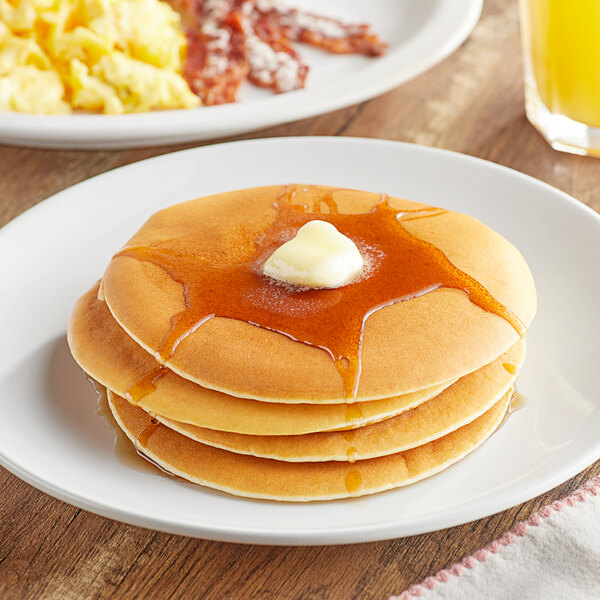 A stack of pancakes with butter on top and syrup on a plate.