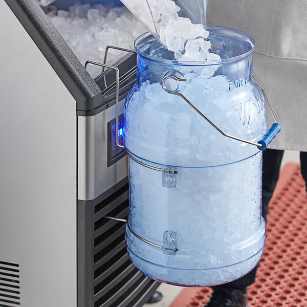 A person pouring ice from a blue Vigor ice tote into a large clear container.