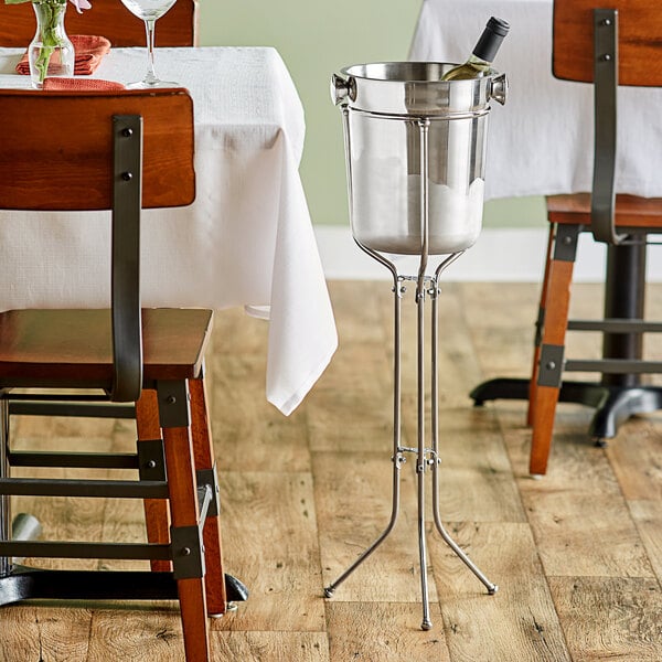 An Acopa stainless steel wine bucket stand with a wine bottle in a bucket.