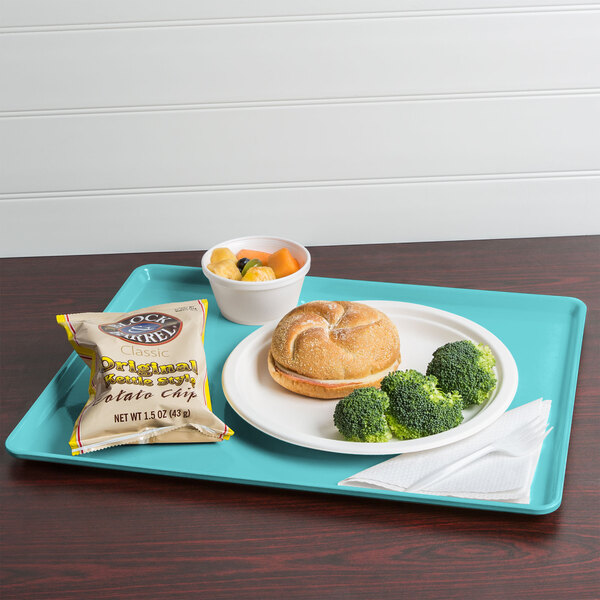 A Cambro robin egg blue dietary tray with a sandwich, broccoli, and potato chips.