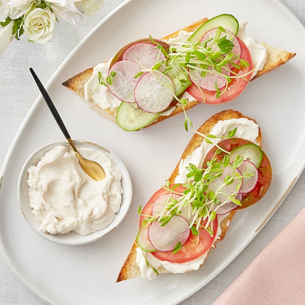 A plate of food with two slices of bread, radishes, and Follow Your Heart Vegenaise.