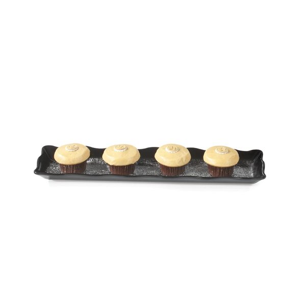 A black rectangular melamine tray with four cupcakes with frosting on them.