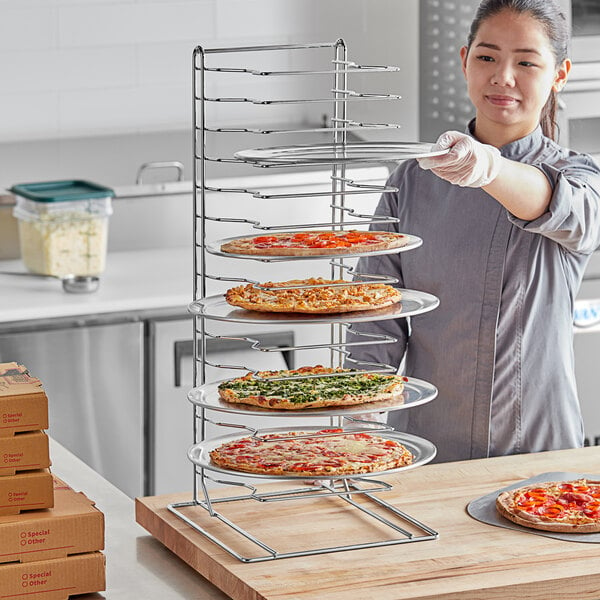 A woman holding a Choice pizza pan rack with pizzas on it.