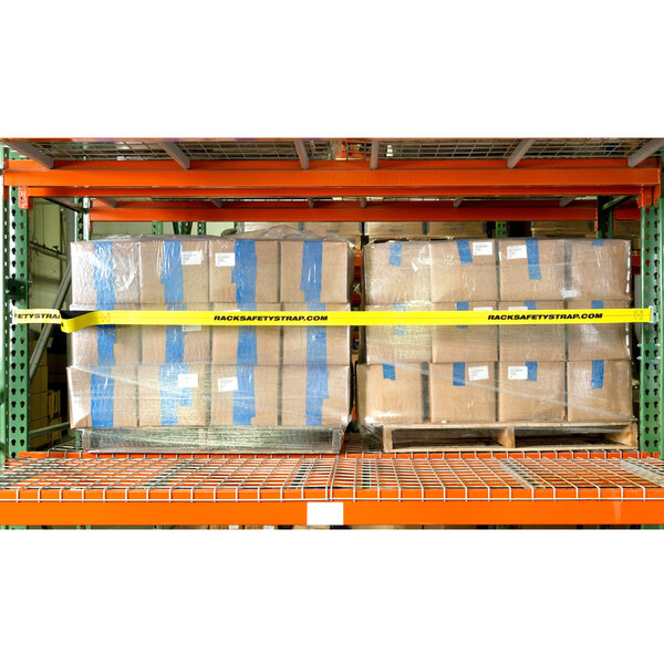 A rack with a stack of boxes wrapped in plastic with yellow tape secured by a yellow safety strap.