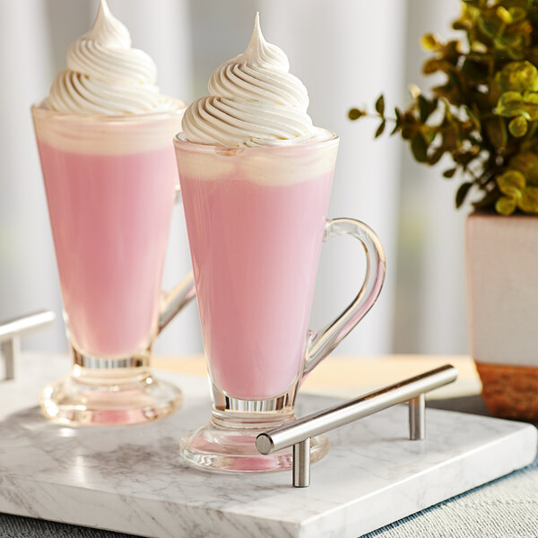 A glass of pink Land O Lakes Cocoa Classics Strawberries and Creme white chocolate cocoa mix with whipped cream on top.