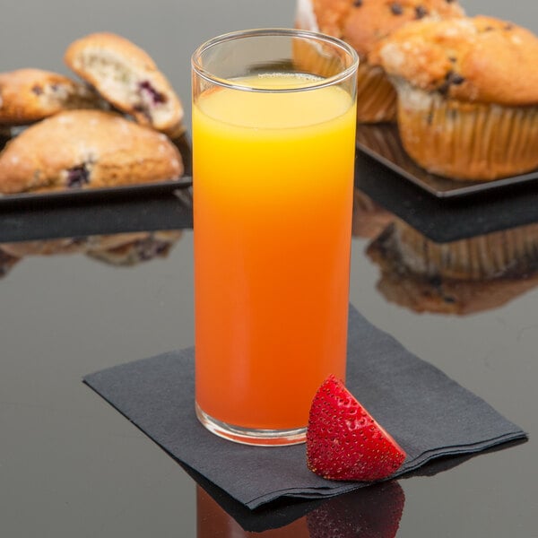 A Libbey straight sided glass of orange juice next to a strawberry and muffins.