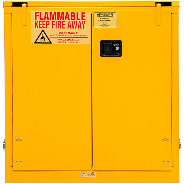 A yellow Durham Mfg flammable storage cabinet with a warning sign.