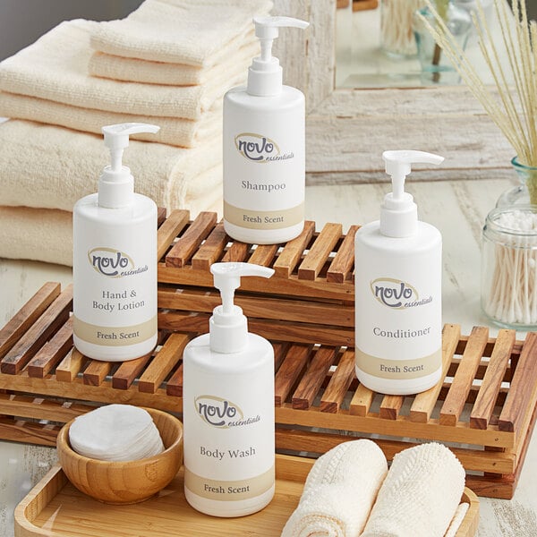 A wooden tray with a variety of white bottles of Novo Essentials Hotel and Motel Toiletries.