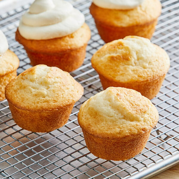 A group of Pillsbury Bakers' Plus white cupcakes with white frosting on a cooling rack.