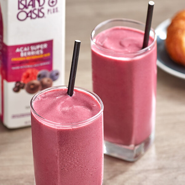 Glasses of pink Island Oasis Acai Super Berries smoothies with straws on a table.