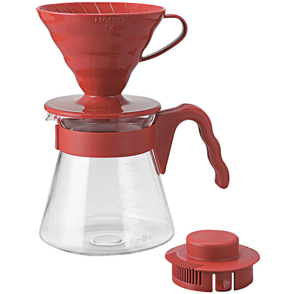A red plastic Hario V60 coffee dripper with a hole and a red handle.