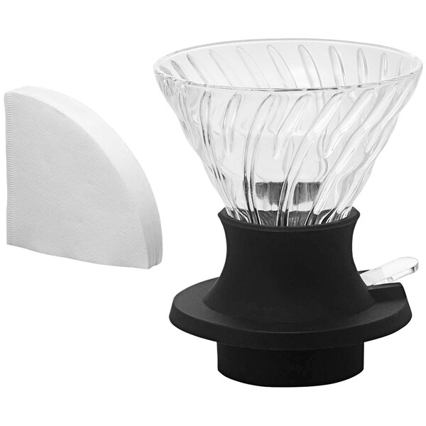A clear glass Hario V60 coffee dripper with a black base and white filters.