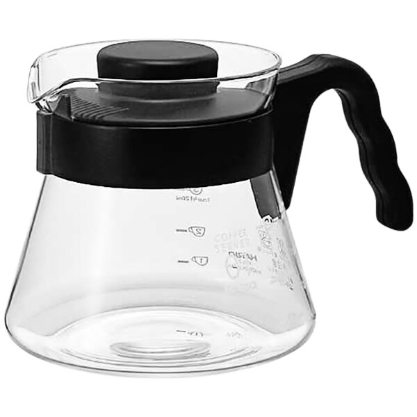 A clear glass coffee pot with a black handle.