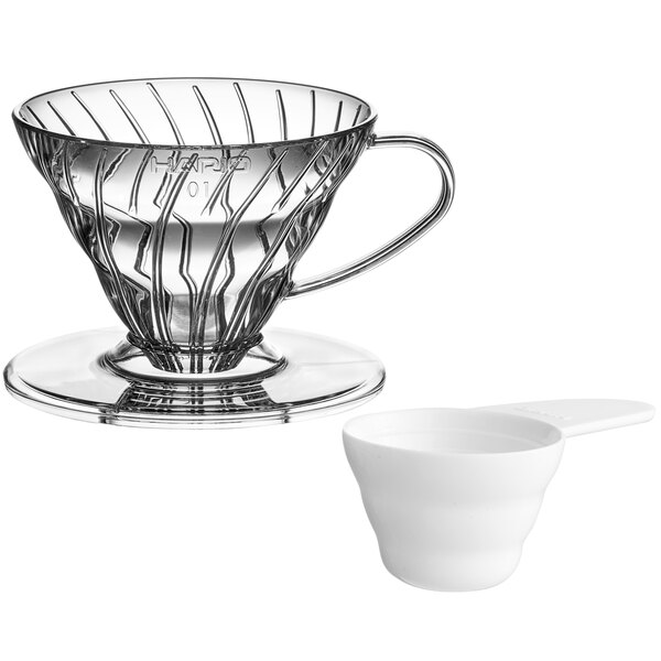 A clear plastic Hario V60 coffee dripper sitting on a white measuring cup.