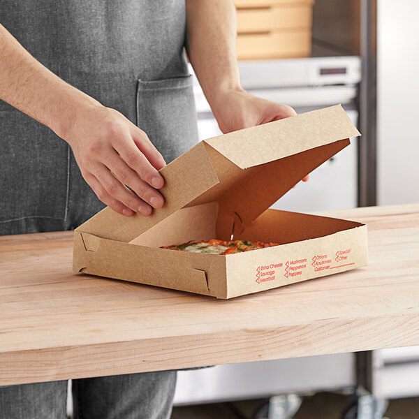 A person opening a Choice Clay Coated Kraft Pizza Box to reveal a pizza inside.