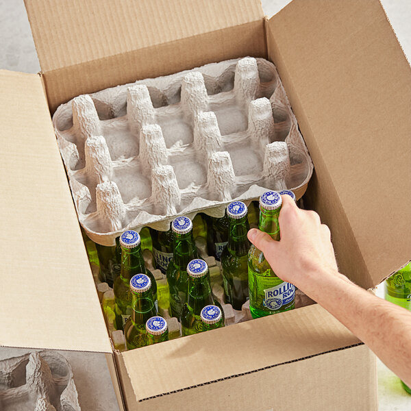A hand putting a green bottle of beer into a Lavex cardboard box.