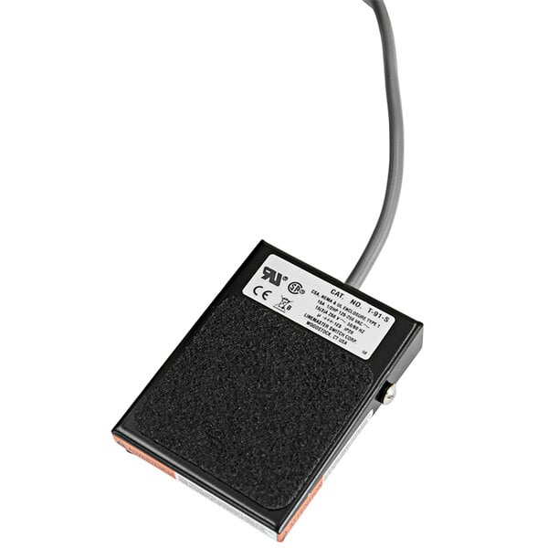 A black rectangular foot pedal with a cord attached.