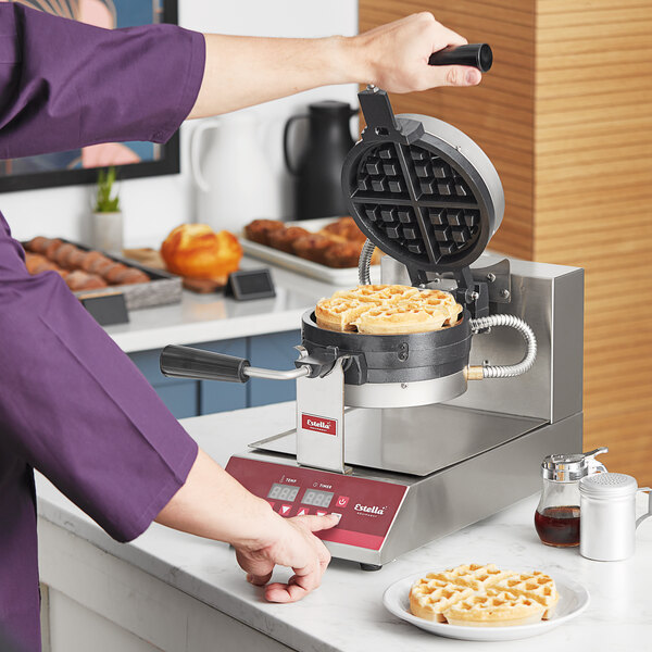 A person in a purple uniform using a Estella Stacked Belgian Waffle Maker to make waffles.