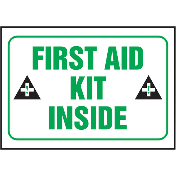 A white sign with green and black text and a black triangle with a white cross and green dots reading "First Aid Kit Inside"