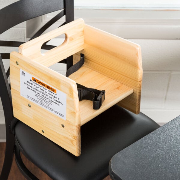 A Lancaster Table & Seating wooden booster seat with a seat belt.