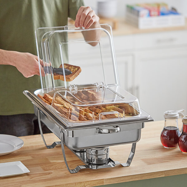 A man using a Choice hinged dome cover to prepare a large chafing dish.