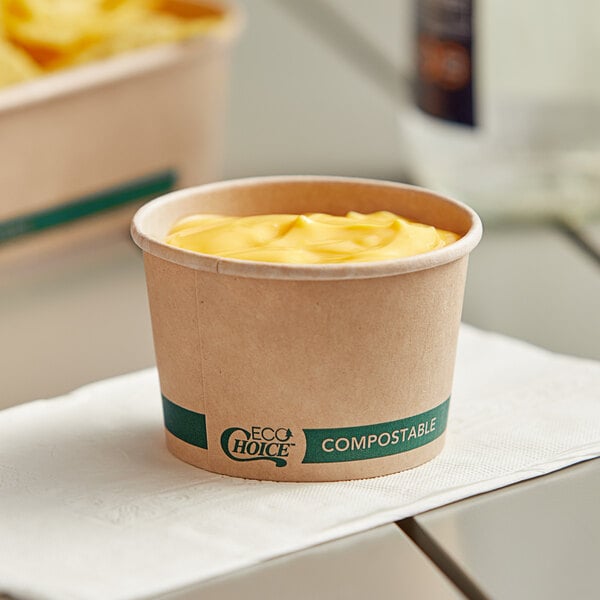 A EcoChoice round kraft take-out container filled with food on a napkin.