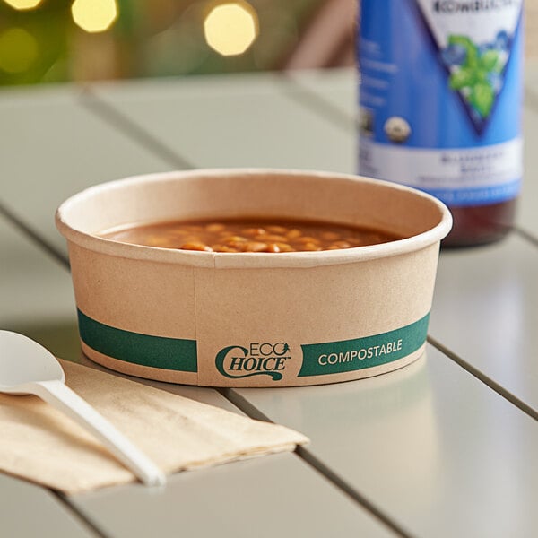 A bowl of beans in an EcoChoice round paper container with a white spoon on a napkin on a table.
