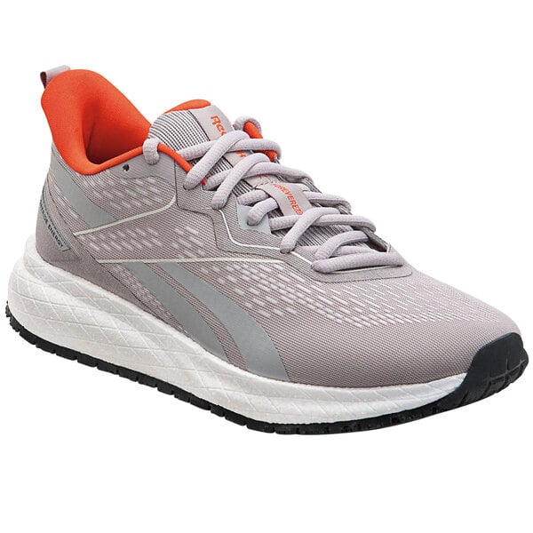 A grey and orange Reebok athletic shoe with a white background.