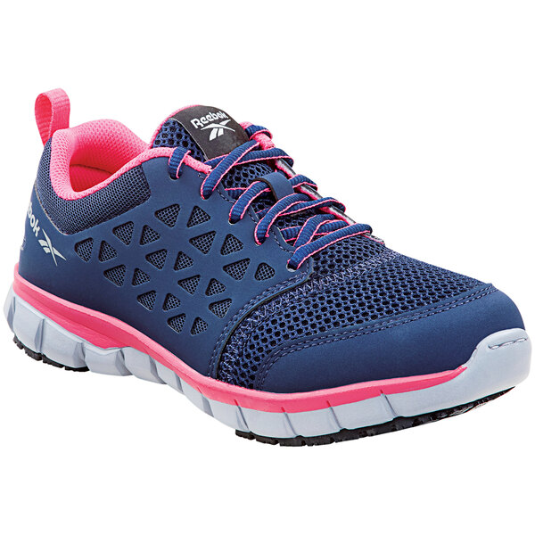 A close up of a navy blue and pink Reebok Work Sublite women's athletic shoe.