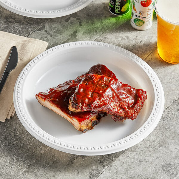 A plate of ribs on a Huhtamaki Chinet white plastic plate.